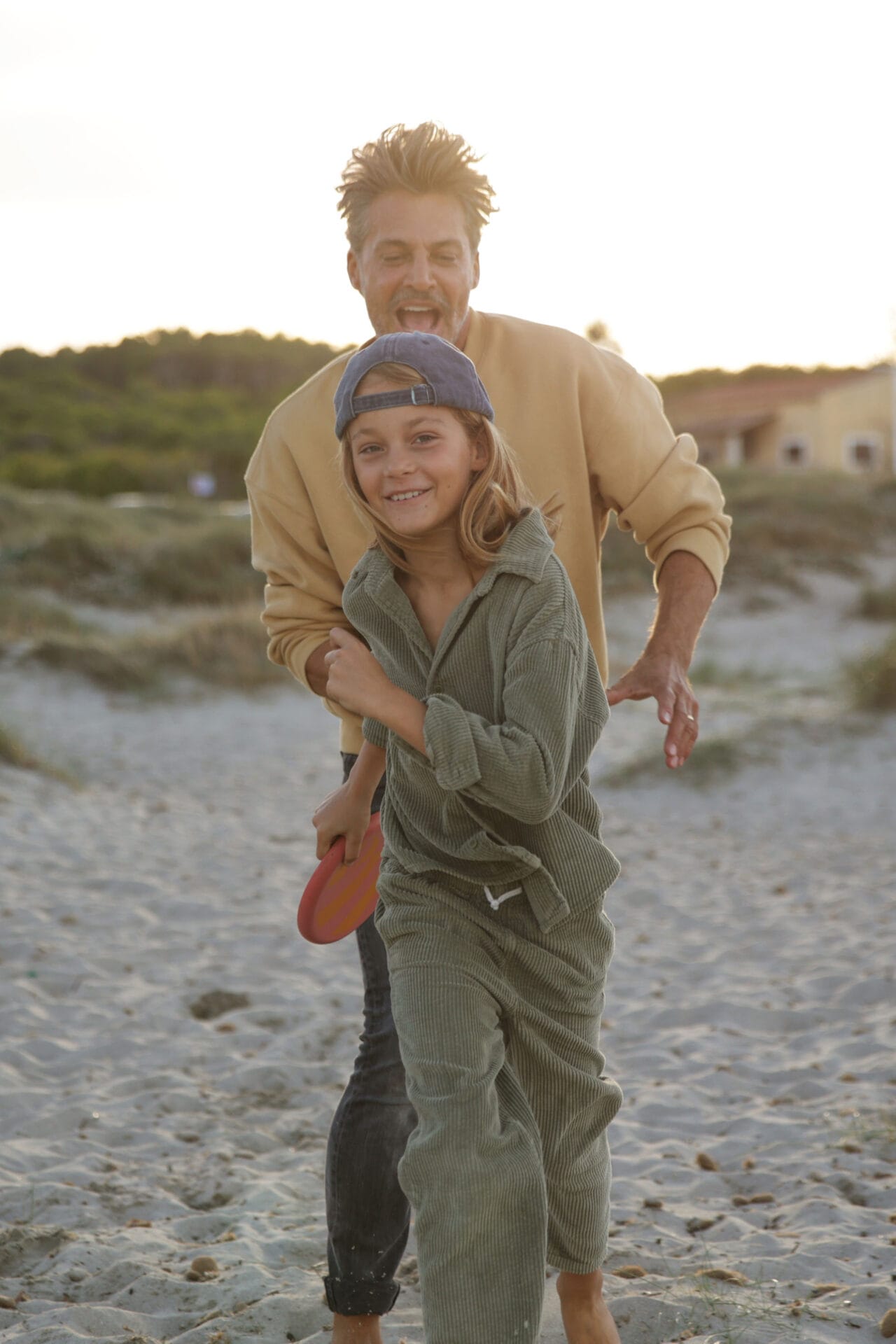 family models father son playing beach frisbee