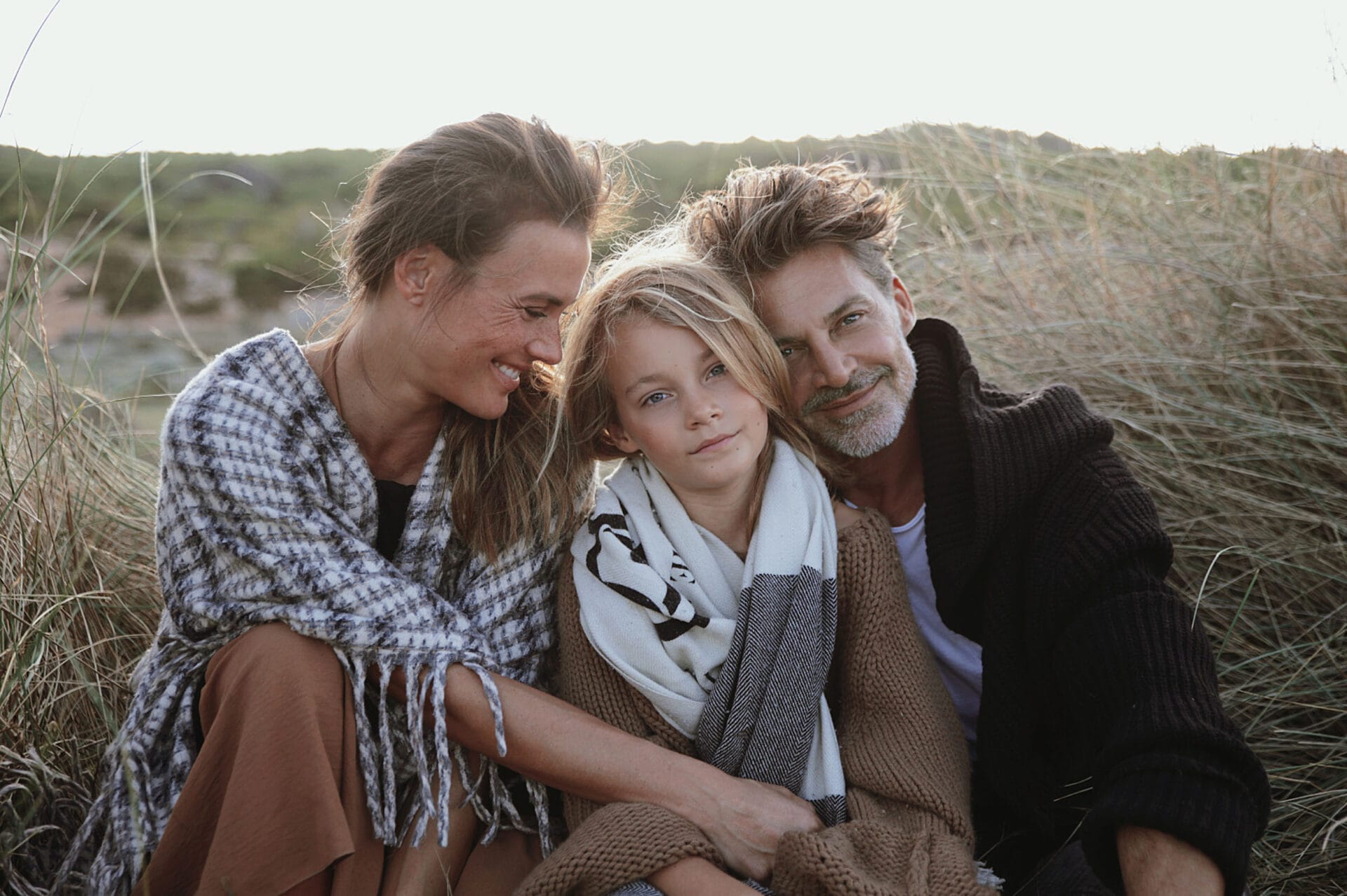 happy mallorca model family sitting in grass by the sea
