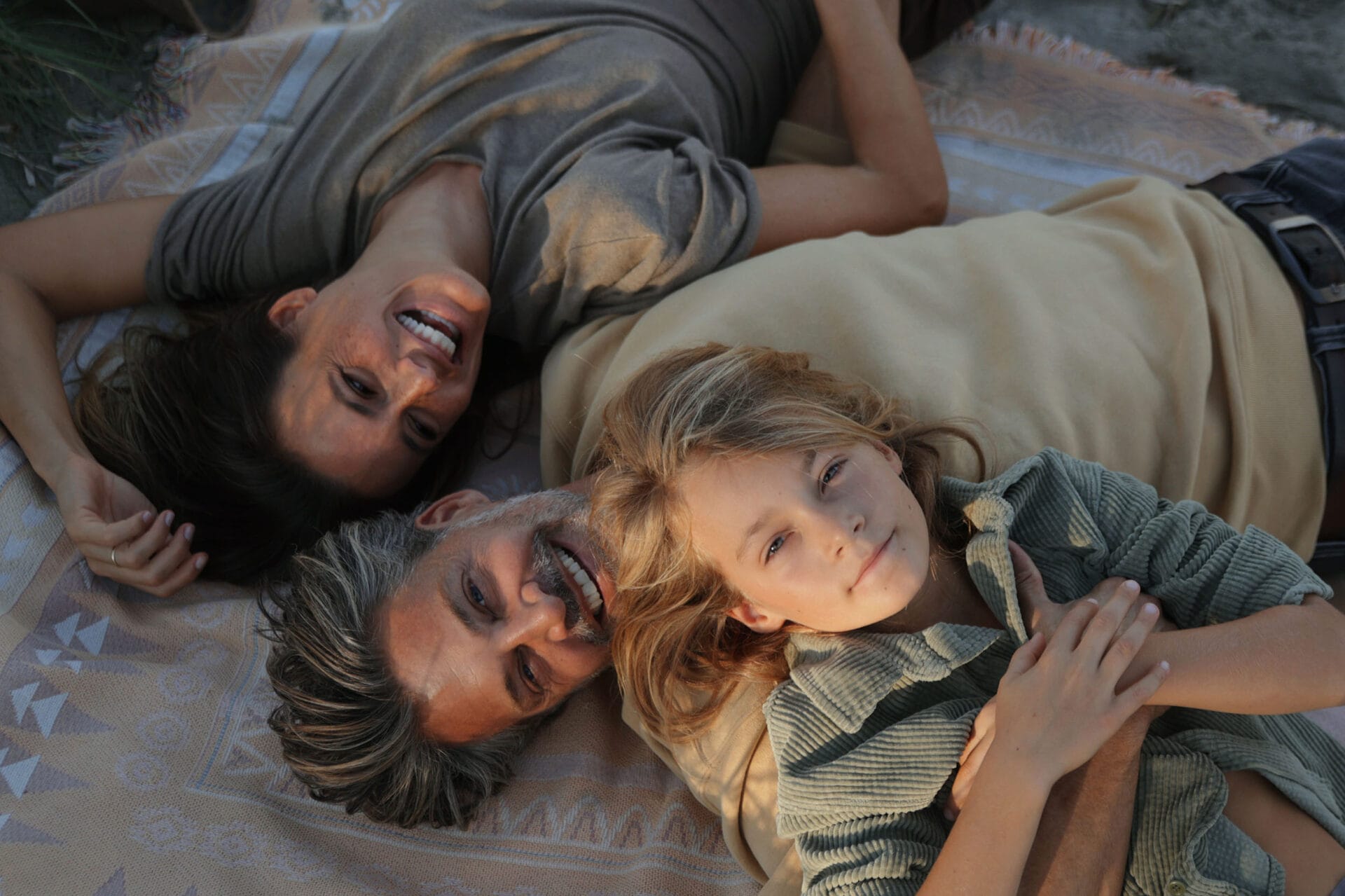 model family father mother son lying on beach smiling